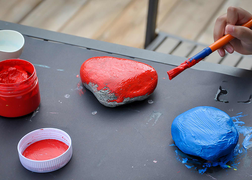 Jar of red paint; 1 rock painted red, 1 rock painted blue