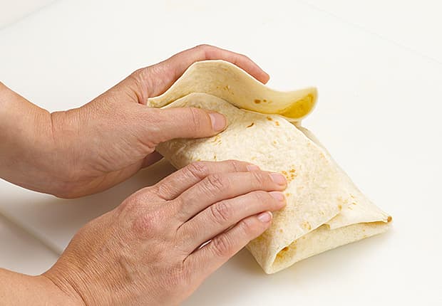 Roll the burrito from the bottom to the top, centering the ingredients as you roll.