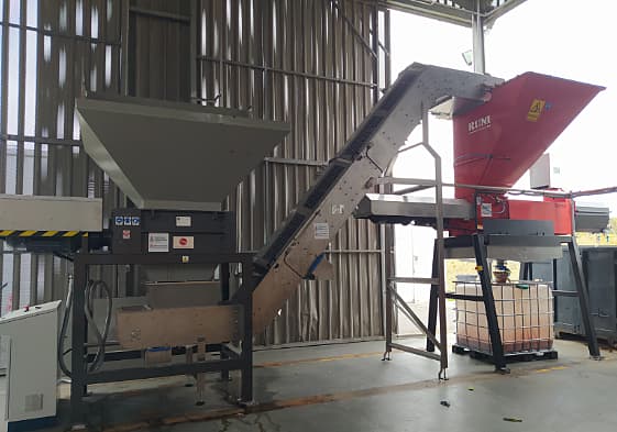A conveyor belt, crushing equipment in a large warehouse