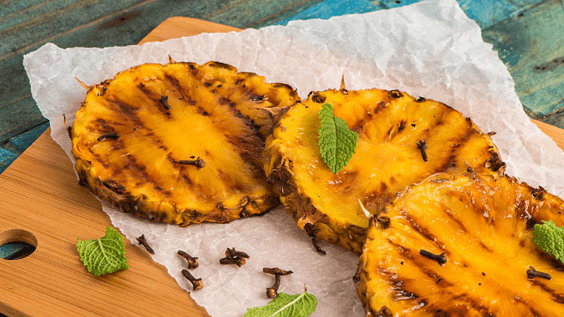 grilled pineapple slices on a wooden board