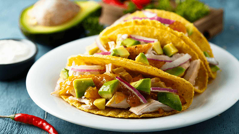 chicken avocado tacos served on a white plate on rustic gray wooden table