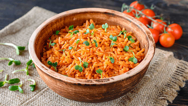 mexican inspried rice served in a bowl with cherry tomatoes by side