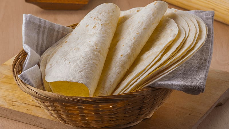 Mexican tortillas in a basket placed on wooden board