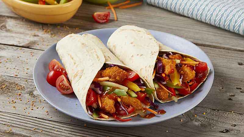 Crunchy Rainbow Chicken Fajitas served on light blue plate on rustic wood table