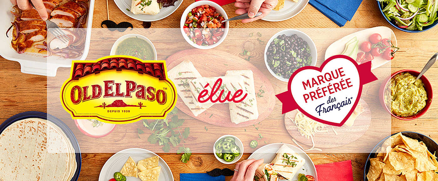 a table with a spread of ingredients such as tortillas, cheese, meat, chilli, nachos etc. featuring old el paso brand logo & red heart shaped logo
