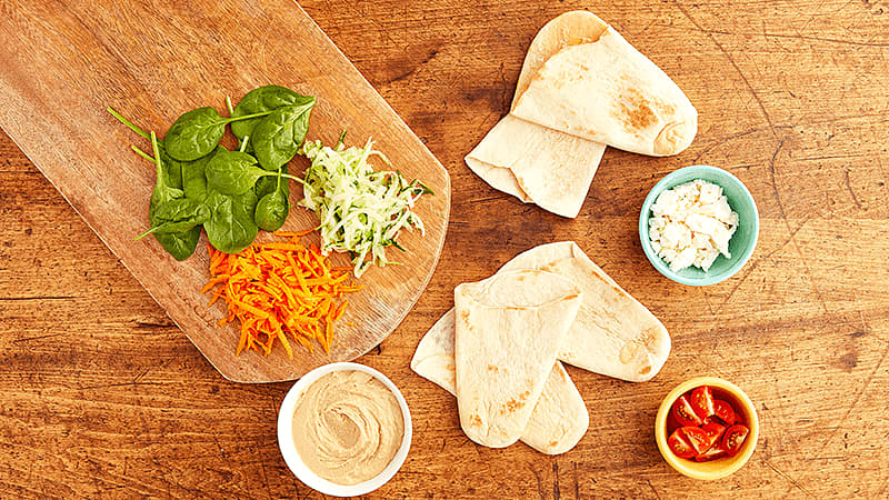 ingredients of mediterranean tortilla pockets placed on wooden table