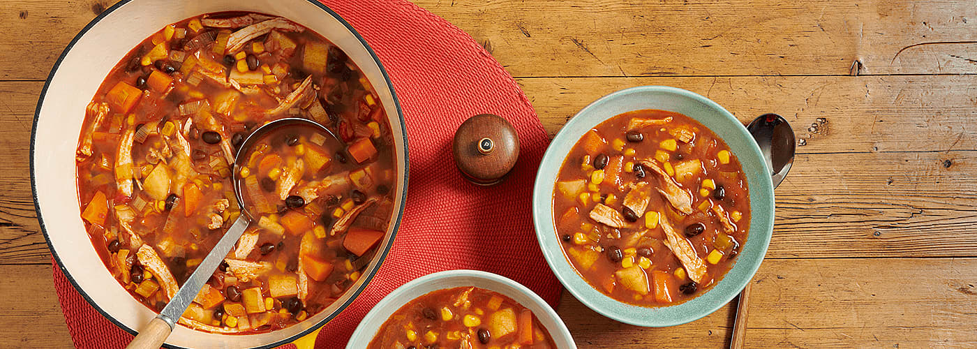 chilli soup served in a bowl accompanied by a soup pot on wooden table