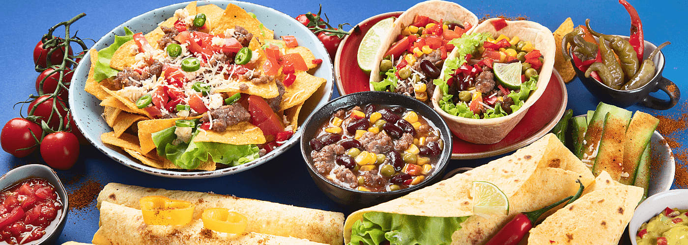 delicious mexican dishes including tacos, fajita, nachos, bean soup etc. served on table
