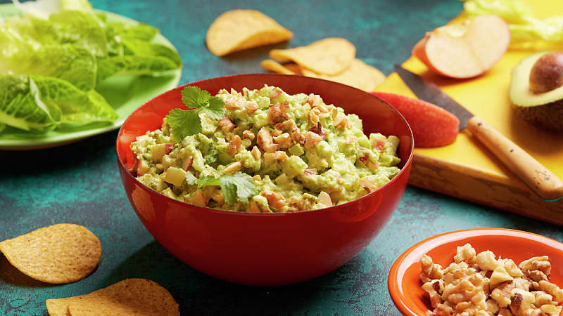 a bowl filled with Crunchy Waldorf Guacamole placed on a table
