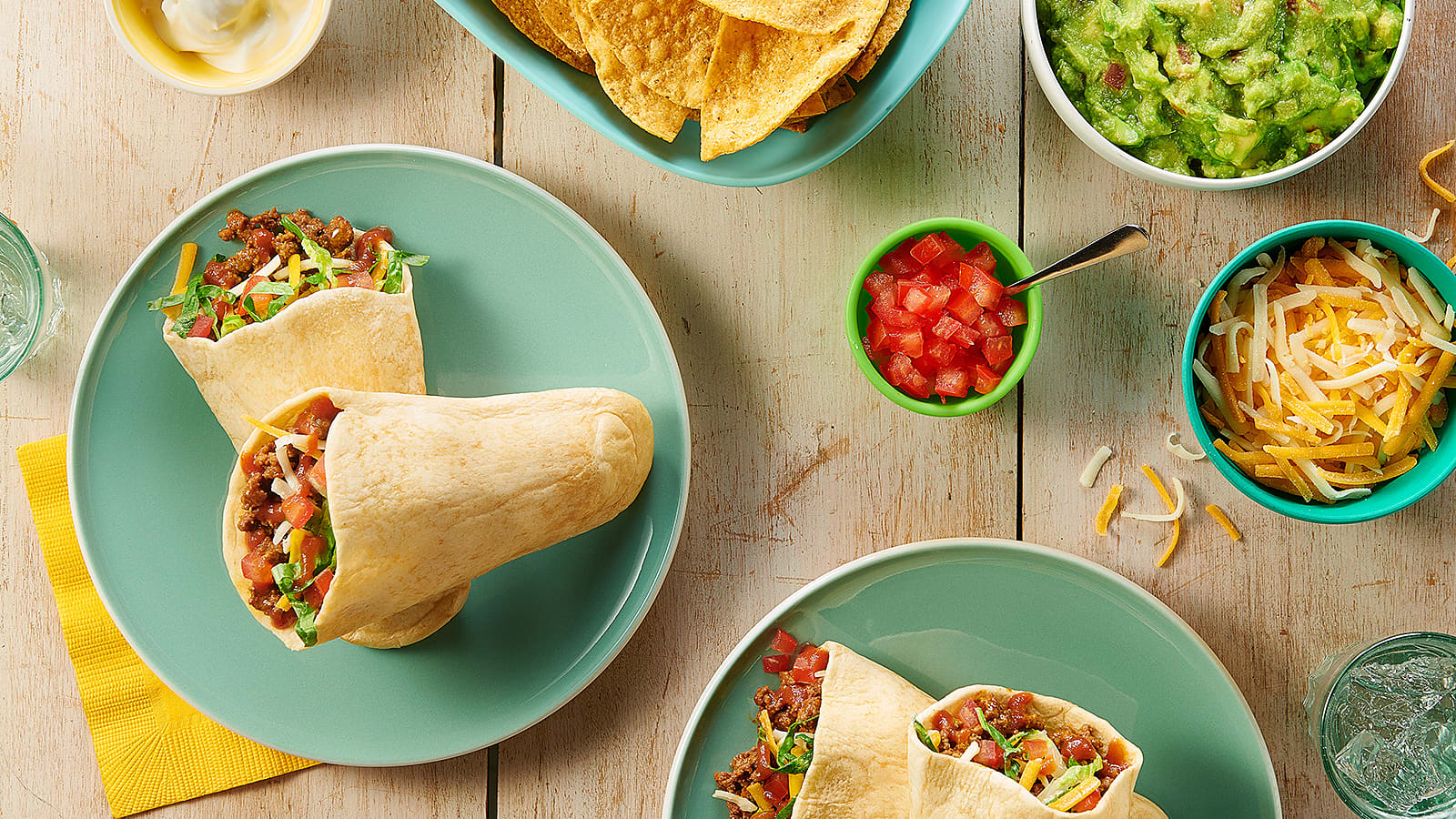 A table holding two plates of tacos and various ingredients