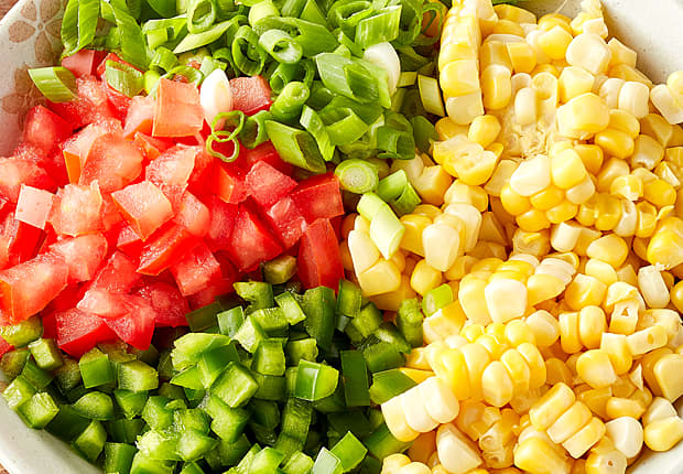 In a large bowl, combine cooked corn, seeded, diced tomatoes, sliced green onion and seeded, minced jalapeno.